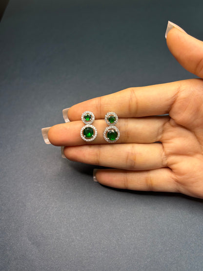Green gemstone earrings held between fingers