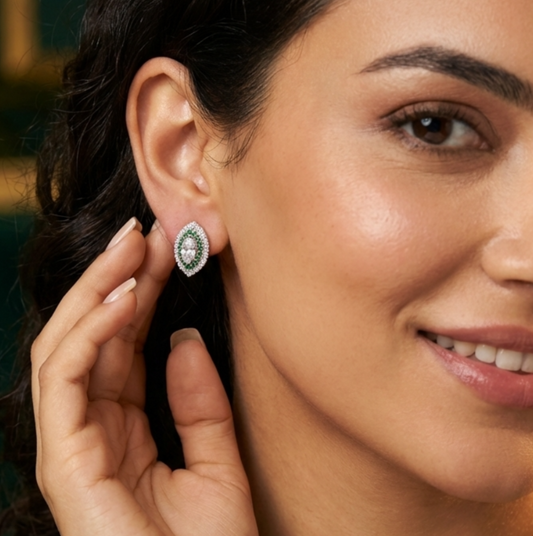 Woman wearing a silver earring with a green gemstone, smiling.
